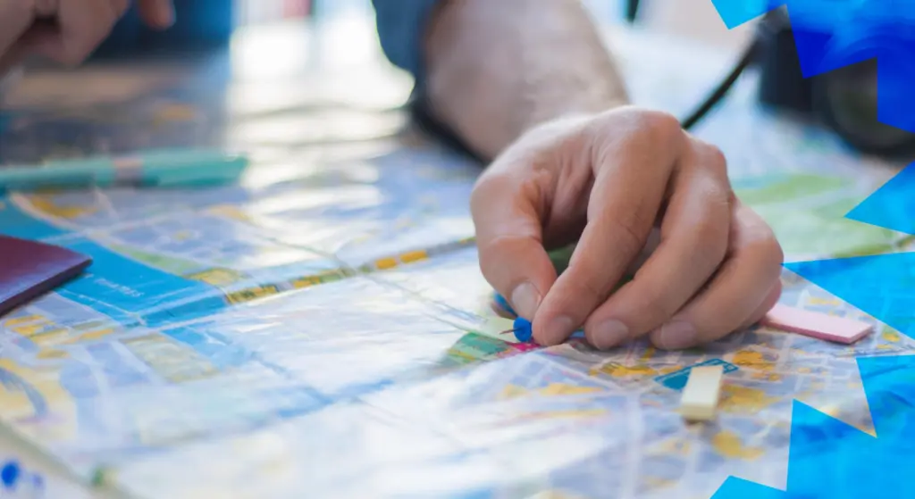 Mano che posiziona una puntina su una mappa, concetto di ricerca partner progetti europei attraverso una piattaforma interattiva.